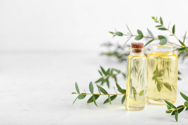 Bottles of eucalyptus oil on light background - Φωτογραφία, εικόνα