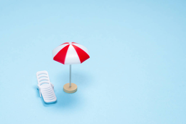 Travel concept. Sun lounger, red umbrella on a blue background. Copy space.  - Fotografie, Obrázek
