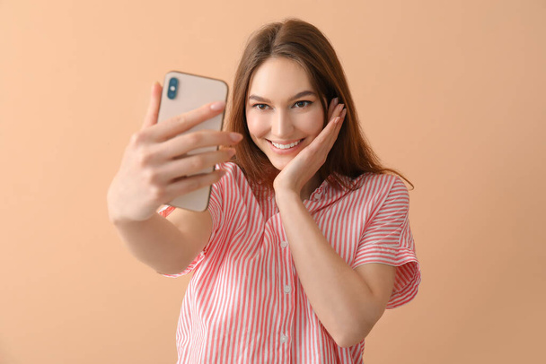Jolie femme souriante prenant selfie sur fond beige - Photo, image