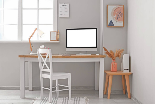 Modern workplace with blank computer screen in light office - Φωτογραφία, εικόνα