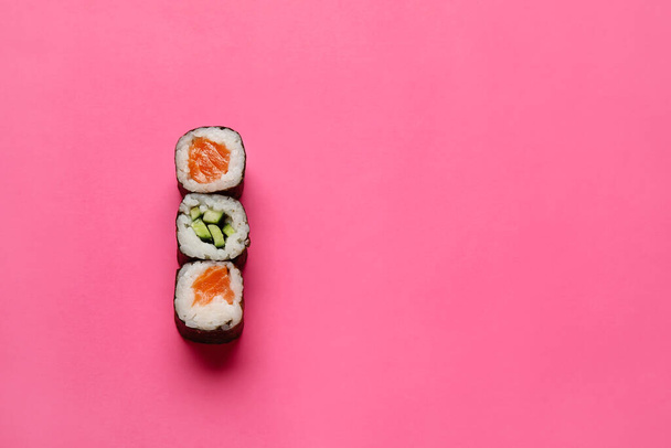 Heerlijke zalm en komkommer maki sushi op kleur achtergrond - Foto, afbeelding