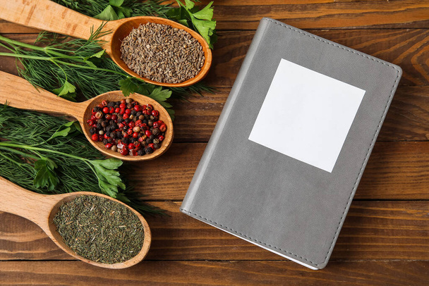 Recept könyv és szilárd kanál különböző fűszerek fa háttér - Fotó, kép