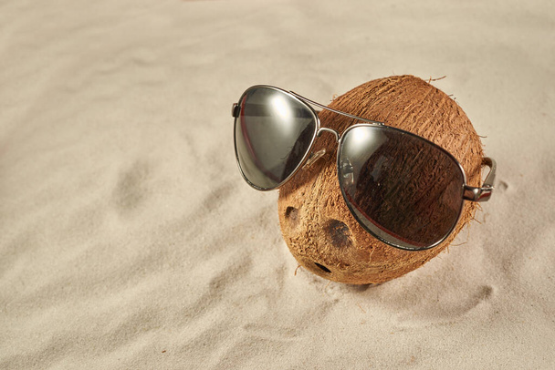 Καρύδα με γυαλιά ηλίου σε μια αμμώδη παραλία - Φωτογραφία, εικόνα