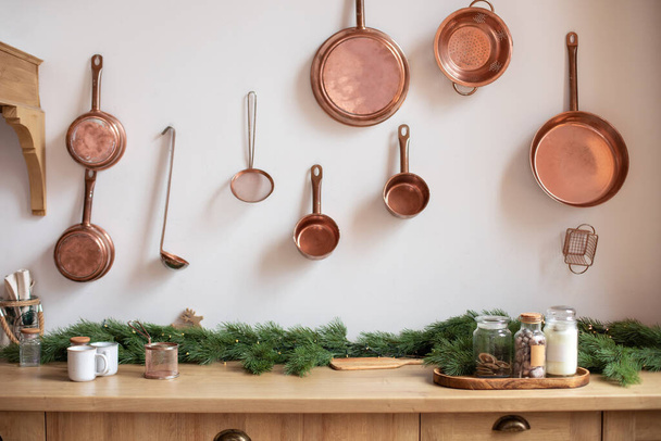 Set of saucepans hanging in kitchen. Hanging Copper kitchen utensil on the white wall. Different kind of vintage copper cookware, pans, pots and funnel on wooden kitchen. Rustic kitchen interior decor - Photo, Image