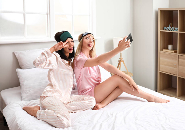 Beautiful young women taking selfie in bedroom - Photo, Image