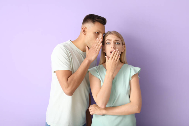 Gossiping young couple on color background - Photo, Image