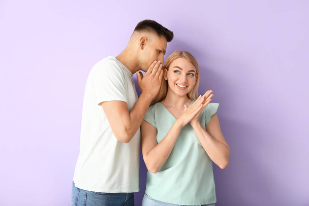 Gossiping young couple on color background - Φωτογραφία, εικόνα