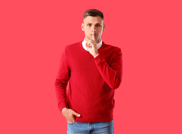Fiatal férfi mutató csend gesztus színes háttér - Fotó, kép