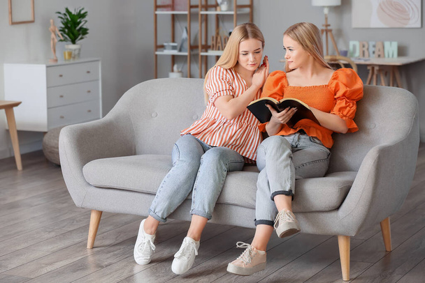 Young twin sisters reading Holy Bible at home - Valokuva, kuva