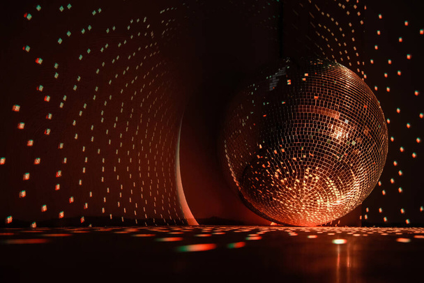 Bola de discoteca que refleja la luz de color naranja quemado en un pasillo oscuro para discotecas. Concepto de vacaciones. Copiar espacio. - Foto, imagen