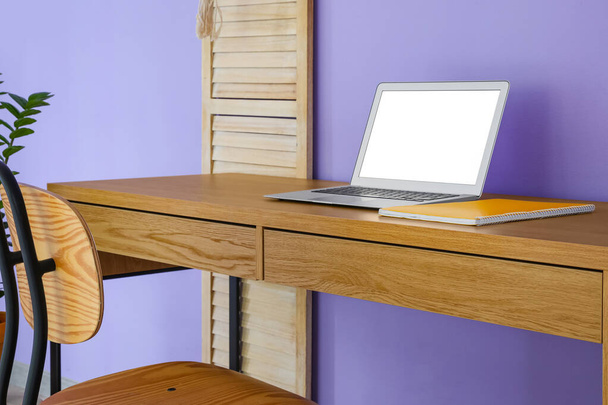 Современный ноутбук и ноутбук на деревянном столе рядом с цветной стеной, крупный план - Фото, изображение