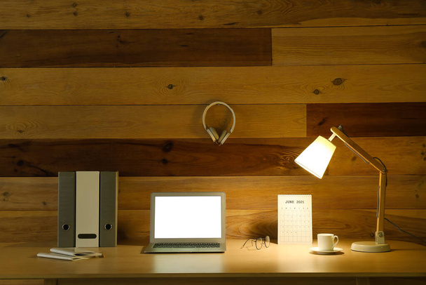 Moderni työpaikka avoin kannettava tietokone ja hehkuva lamppu lähellä puinen seinä - Valokuva, kuva