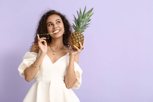 African-American woman with chewing gum and pineapple on color background - Photo, image