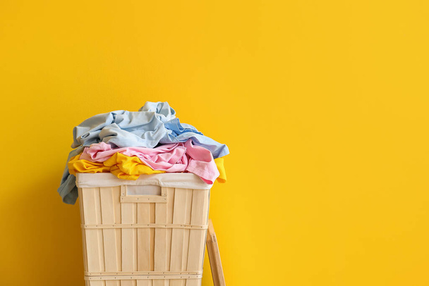 Wooden basket with laundry on yellow background - 写真・画像