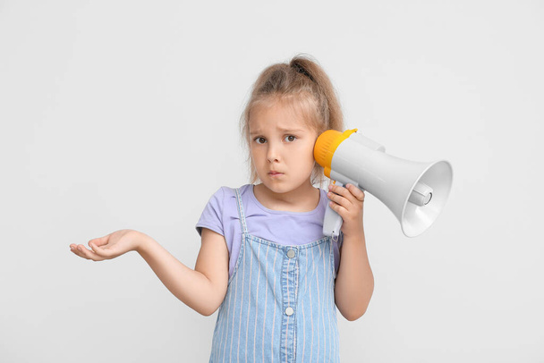 Confused little girl with megaphone on light background - Photo, Image