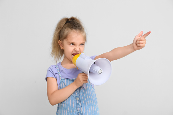 Protestend klein meisje met megafoon op lichte achtergrond - Foto, afbeelding