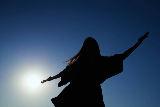 Silhouette girl in dress dancing against sky at sunset - Foto, Imagem