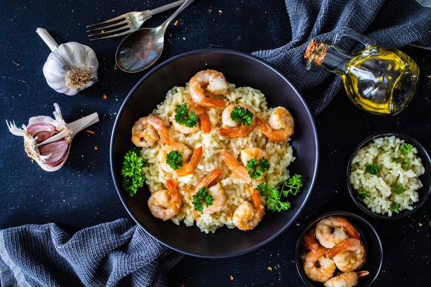 Risotto with prawns, chili and parsley on wooden table - Photo, Image