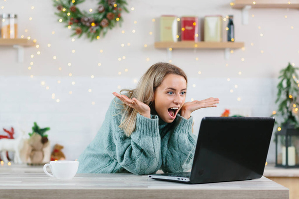 Жінка, шокована щастям, раділа, дивлячись на ноутбук - монітор вдома під час новорічних і різдвяних свят, здивовано дивлячись на новини. - Фото, зображення