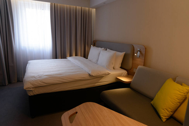 Luxus modern hotel hálószoba, nincs ember, hangulatos meleg színek párnák, szőnyeg, függönyök, falikárpitok és bútorok. Utazás nyaralás relaxációs koncepció. - Fotó, kép