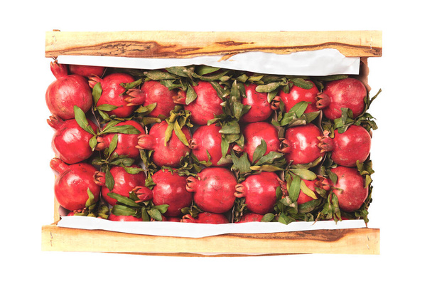 Granadas rojas maduras en una caja de madera. Vista superior, aislado. Entrega de fruta. - Foto, imagen