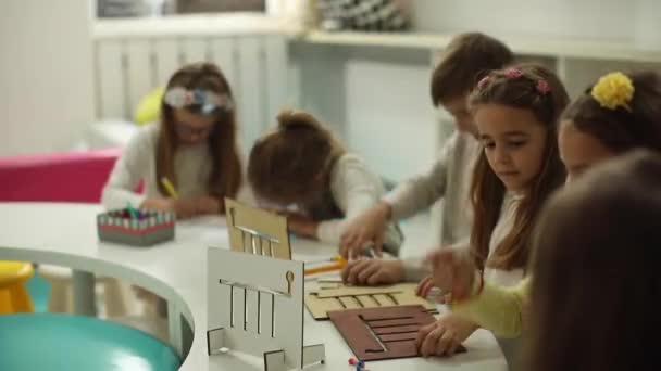 Kisgyerekek csoportja, akik óvodai fából készült oktatási játékokkal játszanak - Felvétel, videó