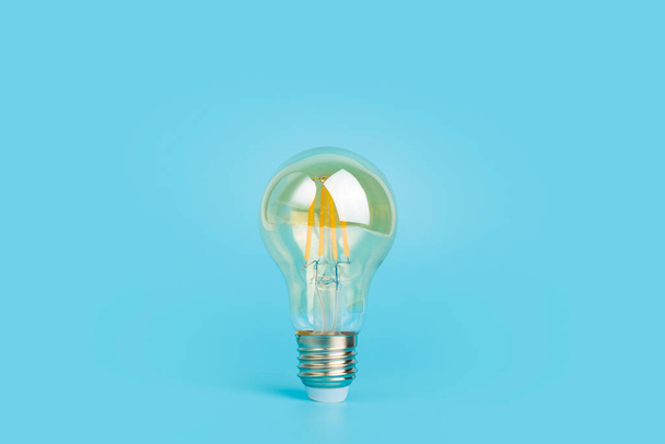 Knowledge and idea concept. Light bulb with light on a blank blue background. Brain, wisdom, knowledge and energy conservation is a creative idea. - Zdjęcie, obraz