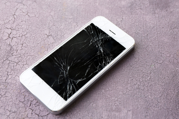 Modern mobile phone with broken screen on wooden background - Foto, afbeelding