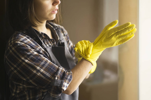 Uma mulher em luvas de borracha amarela faz trabalhos domésticos - Foto, Imagem