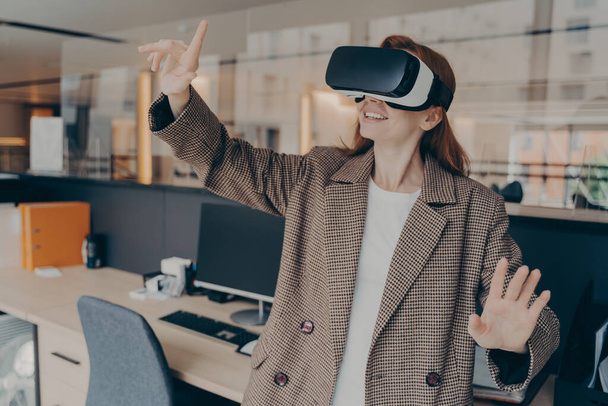 VRヘッドセットで彼女の休憩中に仮想現実ゲームを楽しむ幸せな女性オフィスワーカー - 写真・画像