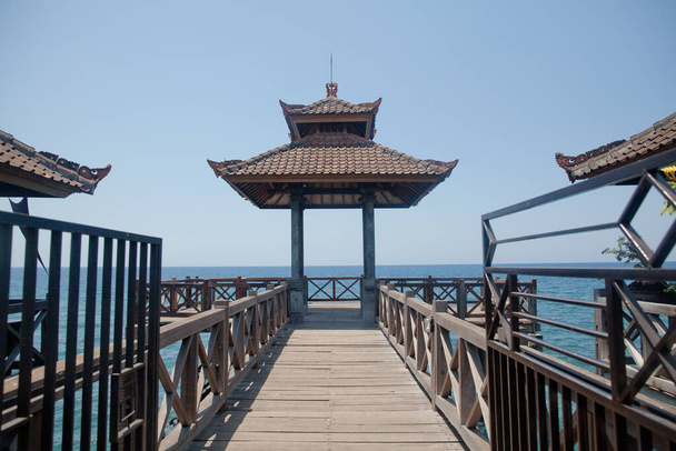 Wooden bridge with a gazebo by the sea. Rest area by the sea. Wooden structure for tourists, Bali - 写真・画像