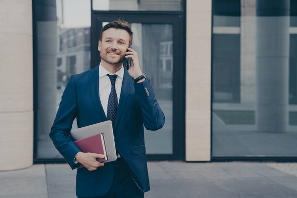 Erfolgreicher und selbstbewusster Unternehmer telefoniert mit seinem Mitarbeiter im Freien - Foto, Bild