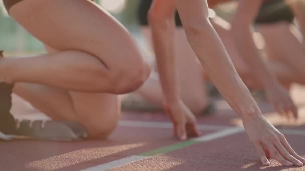 Крупним планом три жіночі треки та спортсмени на стартовій лінії на змаганнях стадіону готуються та тікають у спринтерській гонці
. - Кадри, відео