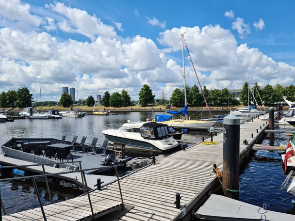 Лодки и яхты пришвартованы на деревянном пирсе в столице Латвии Риге летом 2021 года. - Фото, изображение