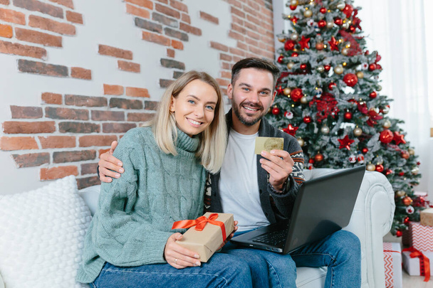 Happy family received confirmation of credit and money on bank account, on credit card, rejoice at home sitting on sofa during New Year and Christmas holidays - Φωτογραφία, εικόνα