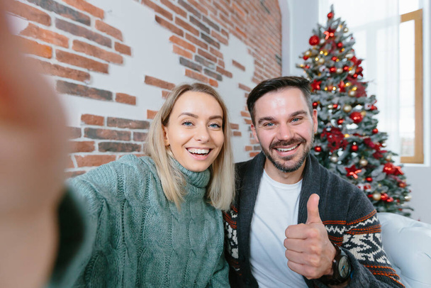 Woman and man at home looking at smartphone camera greet friends with holidays, young family during New Year holidays and Christmas - Foto, Imagen