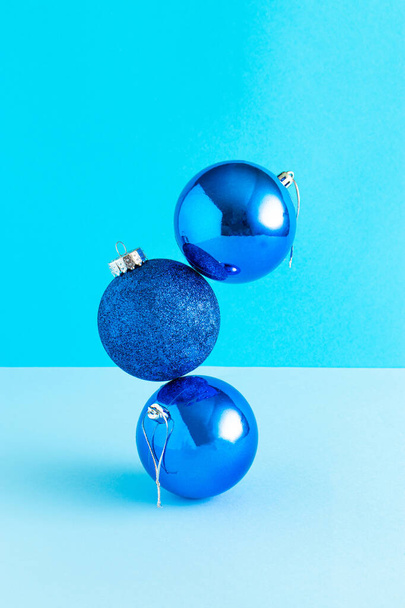 青い背景に青い光沢のあるクリスマスボールとトレンディな組成。最小限の新年のコンセプト。創造的な休日の美学. - 写真・画像