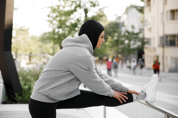 Mujer musulmana estirándose en el entrenamiento al aire libre de la mañana - Foto, Imagen