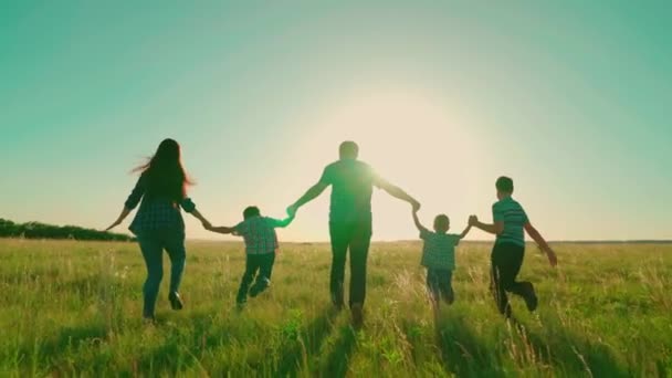 Happy family runs in park holding hands. Happy family walk silhouette of parents and children at sunset. Mom, dad sons walk together outdoors. Family holiday in nature, childrens dreams and fantasies - Footage, Video