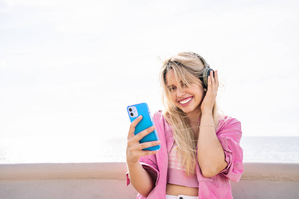 Frau mit Kopfhörer macht Selfie am Strand - Foto, Bild