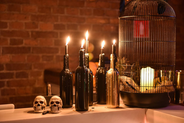 Still life with two skulls, wine bottles, candle light, against the background of a granite table - Halloween or esoteric concept. - Foto, afbeelding