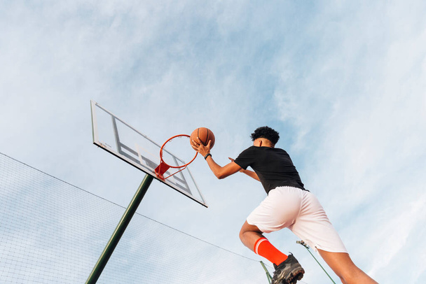 spoko sportowiec rzucający koszykówkę do kosza. Wysokiej jakości zdjęcie - Zdjęcie, obraz