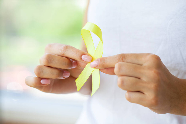 Желтая лента "Женщина, держащая детскую онкологическую сознательность" - Фото, изображение