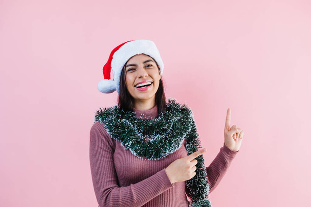 Porträt einer jungen Lateinerin mit Kopierraum in einem Weihnachtskonzept auf rosa Hintergrund - Foto, Bild