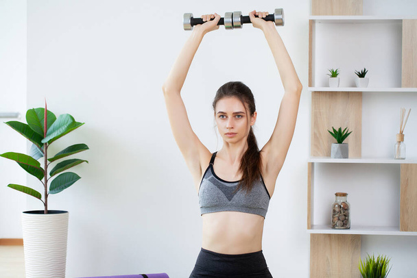 Sporty young woman doing exercising with dumbbells - Photo, Image