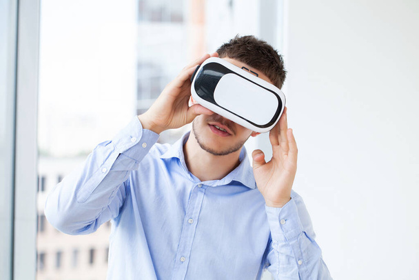 Fiatal férfi visel virtuális valóság szemüveg modern belsőépítészeti coworking stúdió. - Fotó, kép