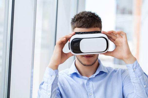 Young man wearing virtual reality glasses in modern interior design coworking studio. - Foto, Bild