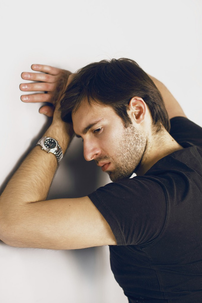 Fashion portrait of an angry handsome smartlooking guy with Brown hair and Bright eyes in a black T-shirt and silver watch on his left hand evil staring into the frame - Φωτογραφία, εικόνα