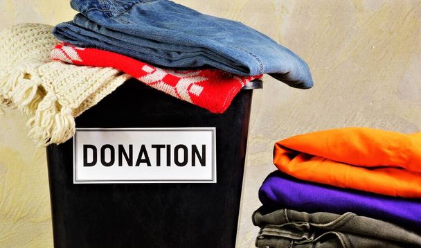 Egy adománygyűjtő doboz ruhákkal. Segíts a rászorulóknak. A jótékonyság fogalma. - Fotó, kép
