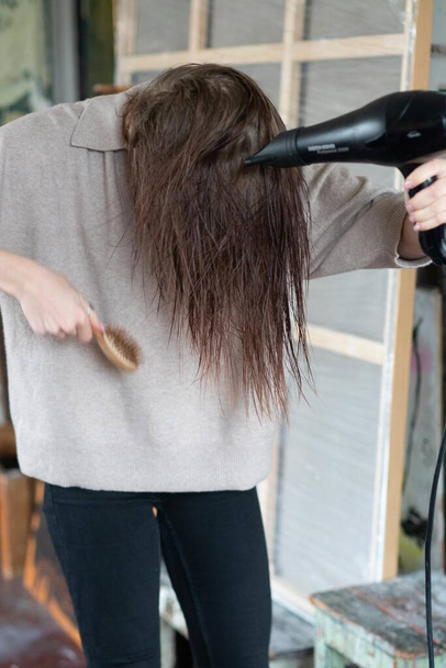 young beautiful woman combing her hair with a hairdryer - Foto, immagini
